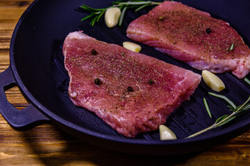 Wall Mural - Raw steaks with garlic, rosemary and spices in a cast iron grill pan