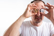 © Nenad - Close up fun emotional  male is holding bitcoin in front eye. Online virtual future currency concept. Handsome man head with Bitcoin money in eyes.