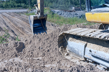 the process of leveling sand with an excavator bucket during the construction of a dirt road