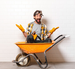 Wall Mural - young bearded construction worker man on a wheelbarrow