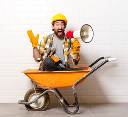 Wall Mural - young bearded construction worker man on a wheelbarrow