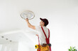 © Angelov - Electrician installs a chandelier on the ceiling. Construction concept