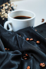 A cup of coffee with flower and book on the dark cloth