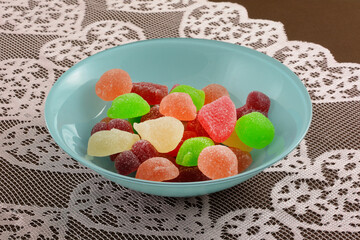 Sticker - Summer fruit pear, apricot, green apple peach and watermelon juice filled gummy candy jellies in blue bowl on lace table runner on tablecloth