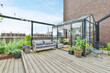 A large open-air terrace on the roof-top with lounge space and a small greenhouse with plants