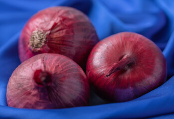 Wall Mural - Whole purple fresh onions on blue tablecloth