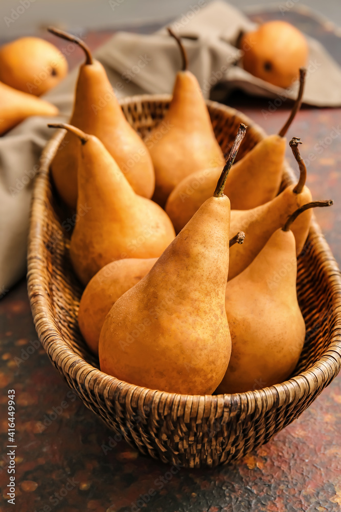 Basket with fresh ripe pears on grunge background