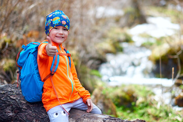 hiking child little girl travel with backpacks thumb up. outdoor sports portrait close-up