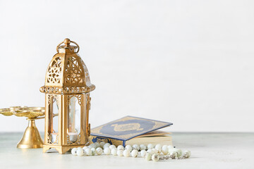 Muslim lamp, tasbih and Koran on light background