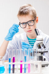 Wall Mural - a schoolboy with a microscope examines chemicals in test tubes, conducts experiments - a portrait on