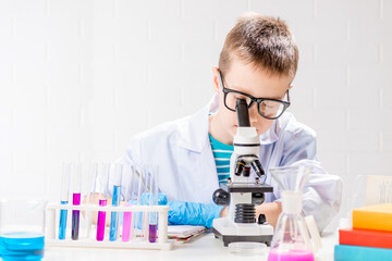Wall Mural - a schoolboy with a microscope examines chemicals in test tubes, conducts experiments - a portrait on