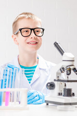 Wall Mural - a schoolboy with a microscope examines chemicals in test tubes, conducts experiments - a portrait on