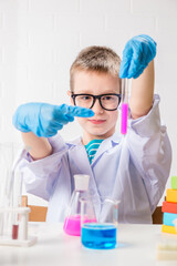 Wall Mural - a schoolboy studies multi-colored substances in test tubes, conducts experiments - a portrait on a w