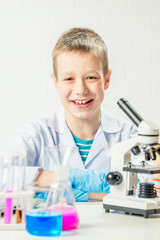 Wall Mural - a schoolboy with a microscope examines chemicals in test tubes, conducts experiments - a portrait on