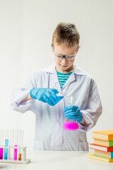 Wall Mural - a schoolboy studies multi-colored substances in test tubes, conducts experiments - a portrait on a w