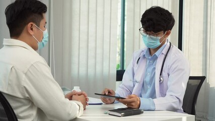 Wall Mural - Doctors are explaining the treatment of a sick patient in tablets while wearing a mask during the virus outbreak.