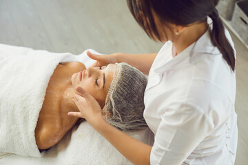 Wall Mural - Face massage. Close-up of young woman getting spa massage treatment at beauty spa salon.