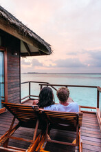 Couple Watching Sunset From Bungalow, Maldives