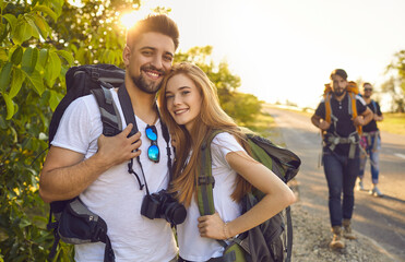 Wall Mural - young couple of tourists with backpacks with friends on a trip in nature.