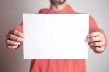 A blank paper sheet in the hands of a young man. Place for inscription, message and image