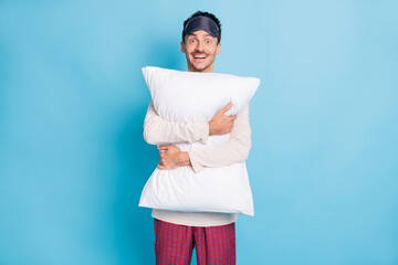 Sticker - Portrait of nice cheerful funny guy wearing sleep clothes embracing soft pillow isolated over bright blue color background