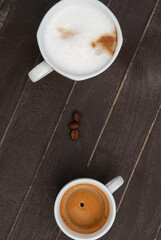 Expresso coffee and cappuccino next to roasted coffee beans on a dark surface. Top view.