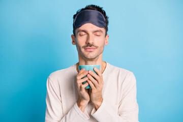 Sticker - Photo portrait of man inhaling coffee aroma holding mug in two hands isolated on vivid blue colored background