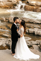 Beautiful wedding couple on the background of a waterfall and a stone river.