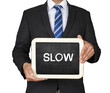 A Businessman holding slate mini blackboard with message Slow