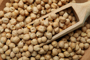 Wooden bowl with scoop and chickpea, close up