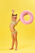 © Rychko Yevhen - cute little child girl in swimsuit and swimming glasses with inflatable rubber ring on yellow background