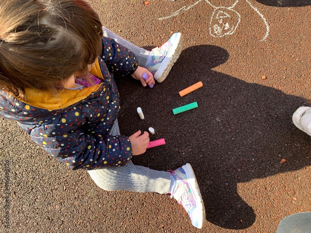 Niña dibujando en el suelo con tizas de colores Stock Photo | Adobe Stock