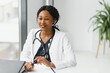 © Serhii - medicine, online service and healthcare concept - happy smiling african american female doctor or nurse with headset and laptop having conference or video call at hospital