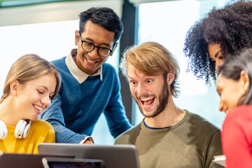 expression of excitement and happiness of a young creative man, multi ethnic teamwork of university students looking at laptop with amazement for the project achievements, successful collaborations