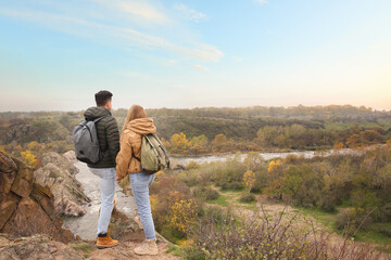 Wall Mural - Couple of hikers with travel backpacks enjoying beautiful view near mountain river