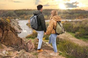 Wall Mural - Couple of hikers with travel backpacks enjoying beautiful view near mountain river