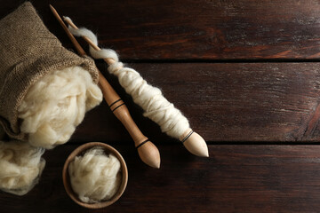 Wall Mural - Soft wool and spindles on white wooden table, flat lay. Space for text