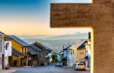 Wall Mural - View of the main street of the small village of Turienzo Castañero in the Bierzo region of Spain, with partial out of focus view of religious cross.