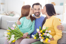 Photo Of Cheerful Family Happy Positive Smile Mom Daughter Kiss Dad Grateful Present Flowers Bouquet Home