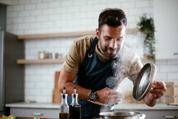 Wall Mural - Handsome man preparing pasta in the kitchen. Guy cooking a tasty meal.