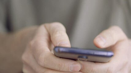 Close-up hands of a man using smartphone. He is typing message on mobile phone.