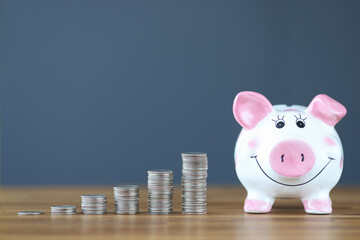 Wall Mural - Pink piggy bank standing on table near heaps of coins