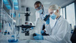 © Gorodenkoff - Modern Medical Research Laboratory: Two Scientists Wearing Face Masks Working Together Using Microscope, Analysing Samples, Talking. Advanced Scientific Lab for Medicine, Biotechnology.