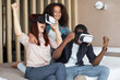 © sofiko14 - Happy multiracial family having fun on weekend, watching movie and playing game in virtual reality glasses, celebrating success, clenching fists and screaming