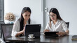 © amnaj - young Asian businesswoman discussing together ideas using a tablet and taking notes. at office.