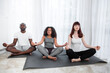 © sofiko14 - Multiracial family of three, sitting in lotus position on yoga mats at home interior. Healthy habits lifestyle and keep calm concept