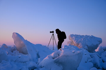 photographer shoots a sunset among the snow-covered hummocks