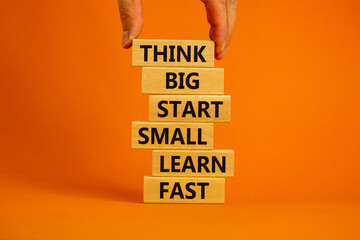 Wall Mural - Think big start small symbol. Words 'Think big start small learn fast' on wooden blocks on a beautiful orange background. Businessman hand. Business, motivational and think big start small concept.