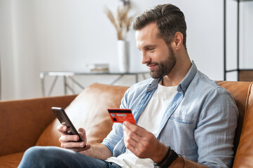 bearded hipster guy businessman, holding mobile phone and credit card for online shopping and enteri