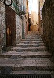 Fototapeta Uliczki - Empty stone paved alley in Old Town Jerusalem, staircase and old buildings